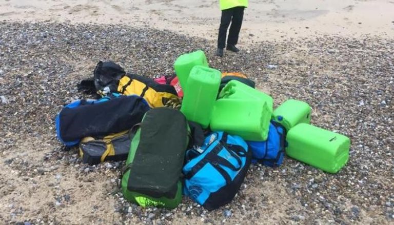 شرطي بجوار حقائب تحتوي على كوكايين قذفتها مياه البحر على شاطئ هوبتون