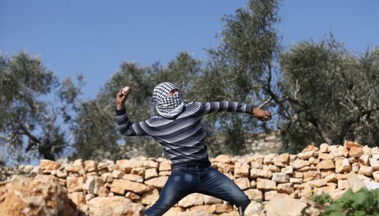 شاب فلسطيني أمام مستوطنة