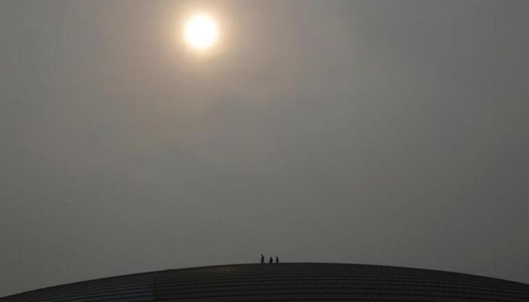 عمال ينظفون سقف المسرح الوطني الكبير في بكين في يوم شهد تلوثا