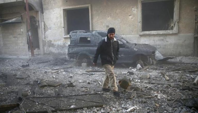رجل يتفقد آثار الدمار الناجم عن ضربات جوية على إحدى ضواحي دمشق