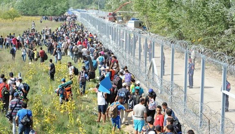 مهاجرون أمام السياج الحدودي بين المجر وصربيا
