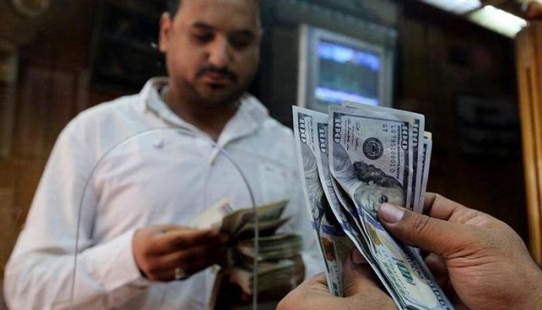 مصري يُبدل دولارات أمريكية بجنيهات مصرية.