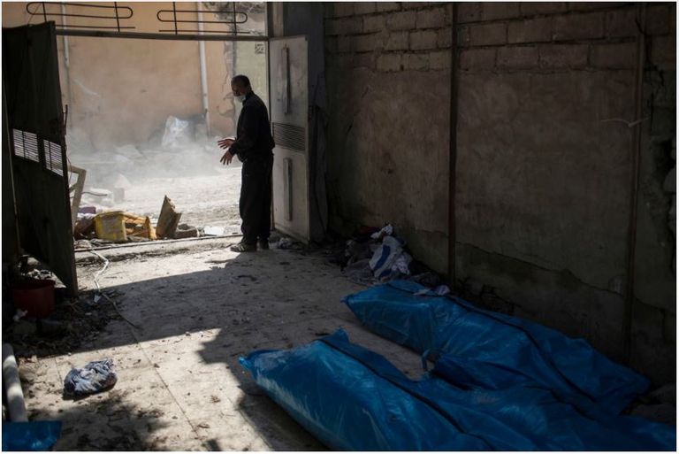 عراقيون بجوار منزل مدمر في الموصل الجديدة