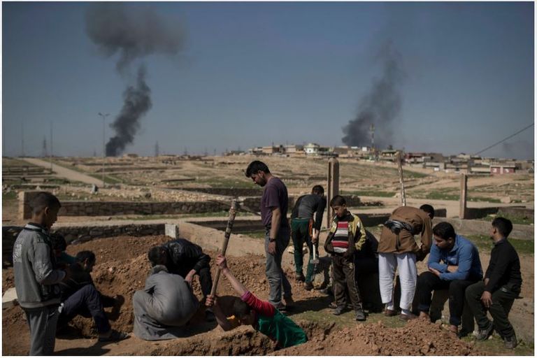 عراقيون بجوار منزل مدمر في الموصل الجديدة
