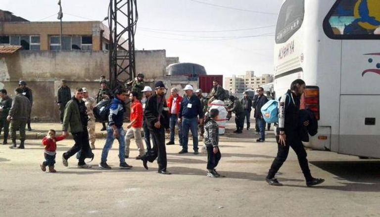 مقاتلون من المعارضة السورية وأسرهم يغادرون حي الوعر في حمص