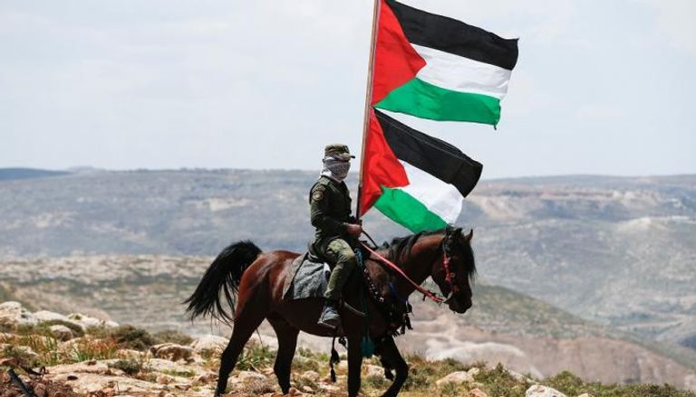 علم فلسطين يرفعه عنصر بأمن السلطة بالضفة الغربية