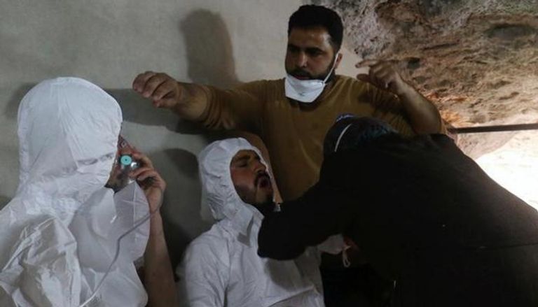 موظف إنقاذ يحمل طفلة من ضحايا الغاز الكيماوي