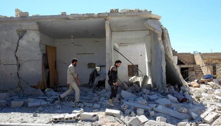 عناصر الدفاع المدني يتفقدون مبنى تعرض لقصف جوي في بلدة خان شيخون