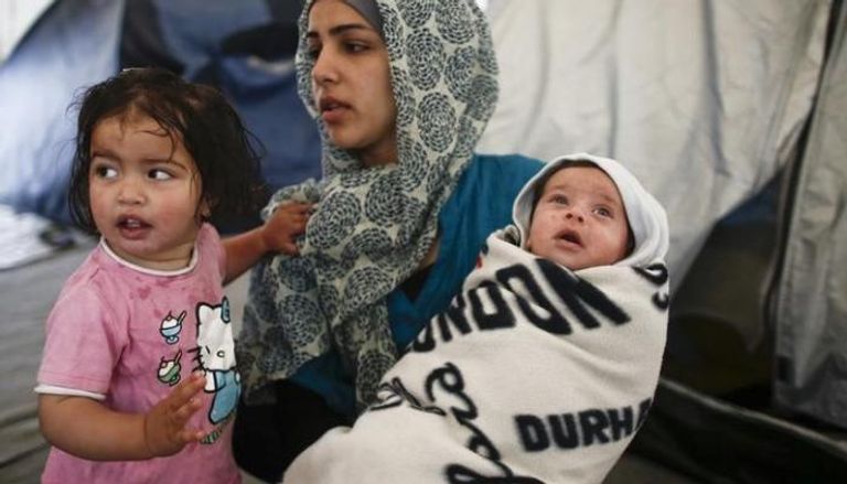 لاجئة سورية تحمل طفليها