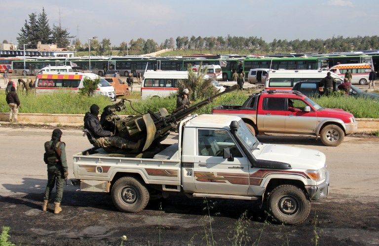 عناصر من المعارضة المسلحة خلال رحيلها من فوعة وكفريا (الفرنسية)