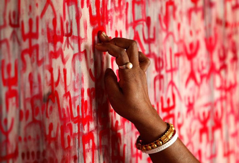 امرأة ترسم الرموز الدينية على جدار معبد في اليوم الأول من السنة البنغالية الجديدة في أغارتالا في الهند. احتفالات رأس السنة البنغالية