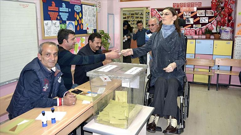 مشرفون يحملون أقصر سيدة بتركيا لوضع ورقتها في صندوق الاقتراع