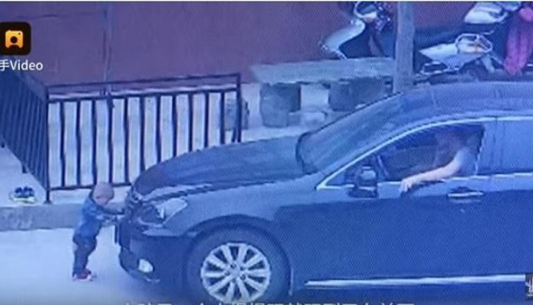 الطفل الصيني أثناء وقوفه أمام السيارة
