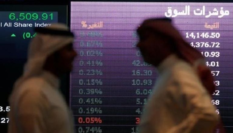   مستثمرون يتحدثون امام شاشة أسهم بورصة السعودية .رويترز