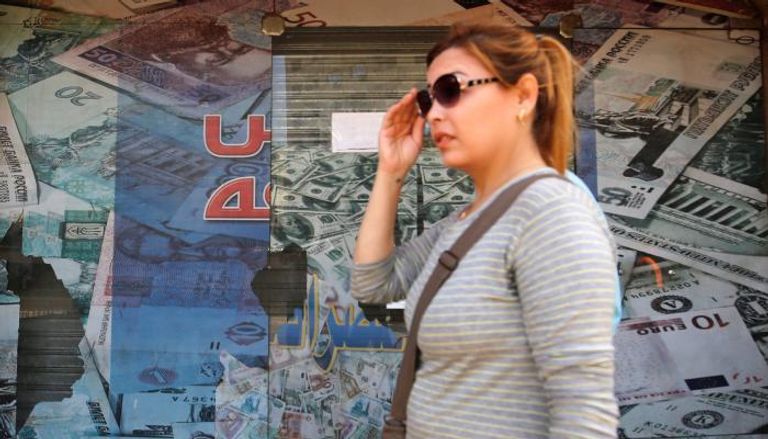 صورة أرشيفية لمصرية تسير بجوار محل للصرافة بالقاهرة
