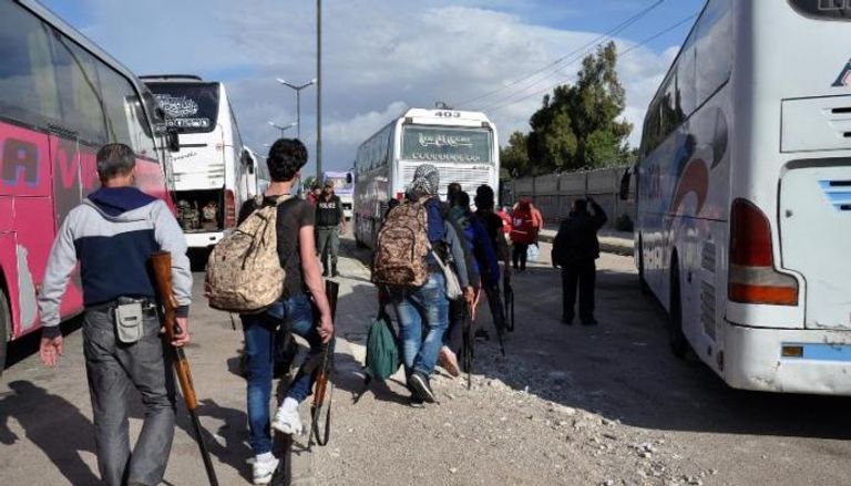 المسلحون خلال خروجهم من حي الوعر بحمص (الفرنسية)
