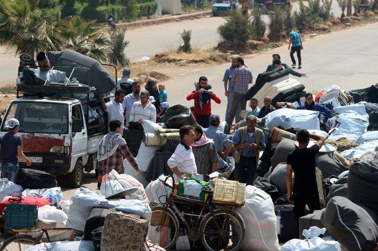 المسلحون خلال خروجهم من حي الوعر بحمص (الفرنسية)