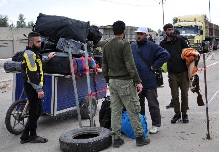 المسلحون خلال خروجهم من حي الوعر بحمص (الفرنسية)