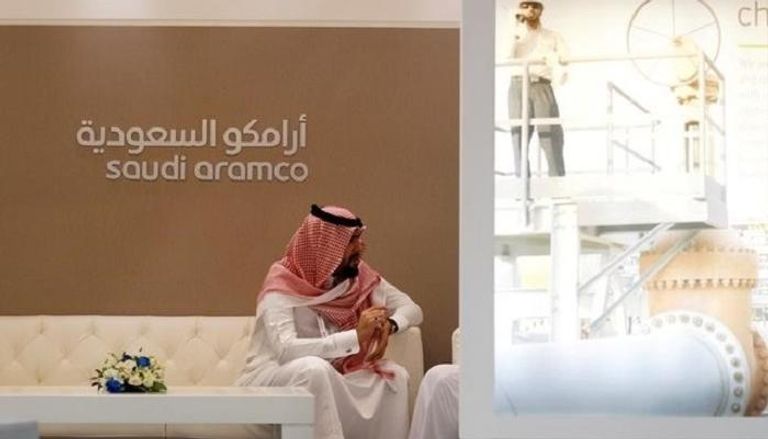  موظف يجلس قرب لافتة تحمل شعار أرامكو السعودية
