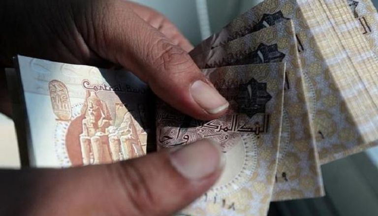 مصري يعد أوراق نقد فئة جنيه مصري– الصورة من رويترز