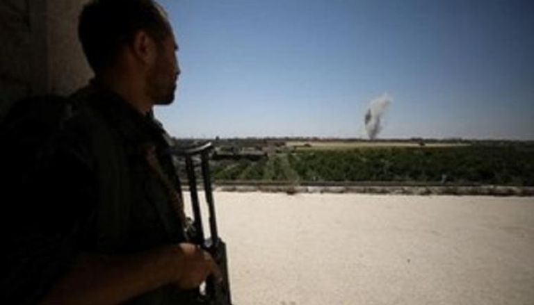 مقاتل من قوات سوريا الديمقراطية يتابع تصاعد دخان من حي المشلب بالرقة 