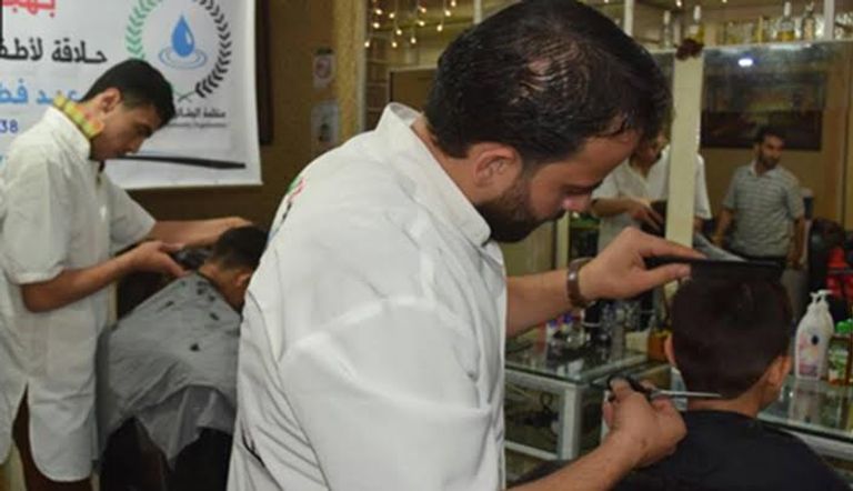 الأطفال ينتظرون دورهم في الحلاقة المجانية