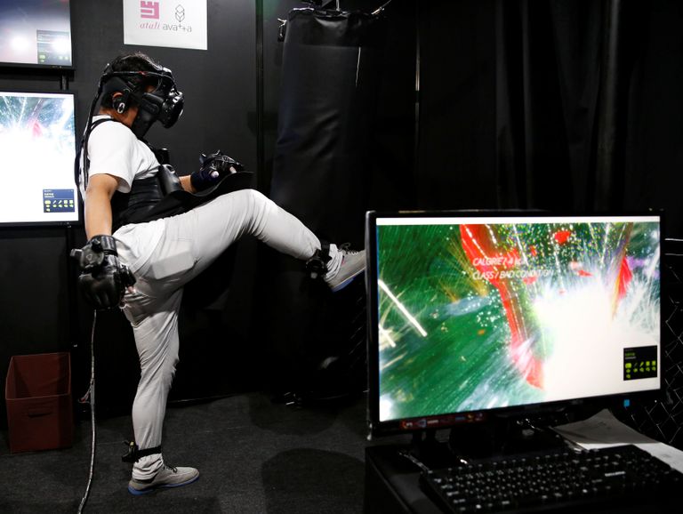 أحد المشاركين بخوذة وقفازات خاصة بالواقع الافتراضي (رويترز)