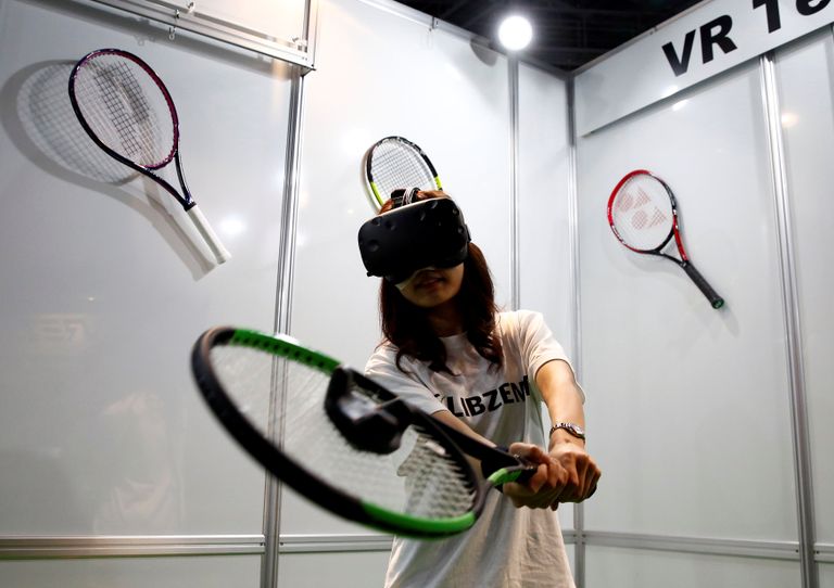 أحد المشاركين بخوذة وقفازات خاصة بالواقع الافتراضي (رويترز)