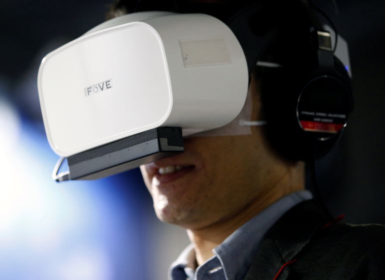 أحد المشاركين بخوذة وقفازات خاصة بالواقع الافتراضي (رويترز)