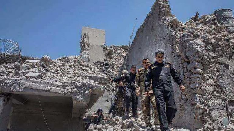 قائد جهاز مكافحة الارهاب خلال تفقدهم اطلال جامع النوري قوات عراقية تلتقط صورا مع علم داعش المقلوب احتفالا بهزيمته (رويترز)