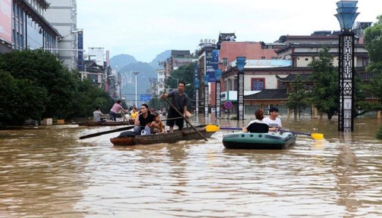 مواطنون يستخدمون القوارب في التنقل بعد أن غمرت مياه الفيضانات الشارع