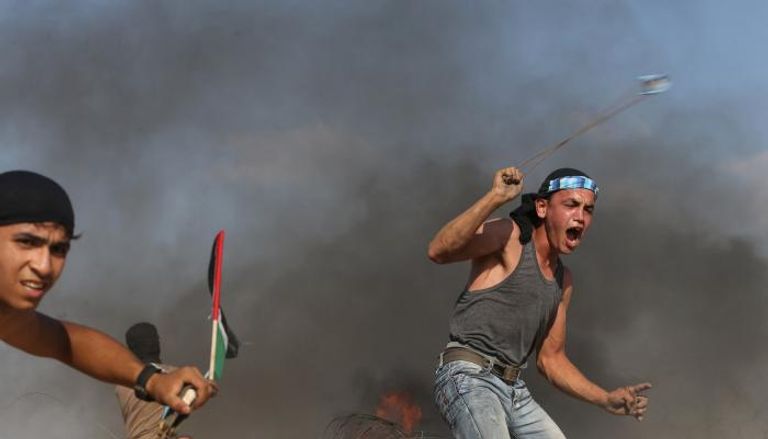 شاب يرشق جيش الاحتلال بالحجارة خلال مظاهرة بغزة - رويترز