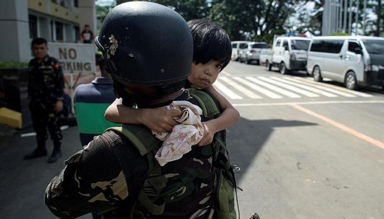 أحد الجنود يحمل طفلة تم إنقاذها من مدينة ماراوي (أ ف ب)