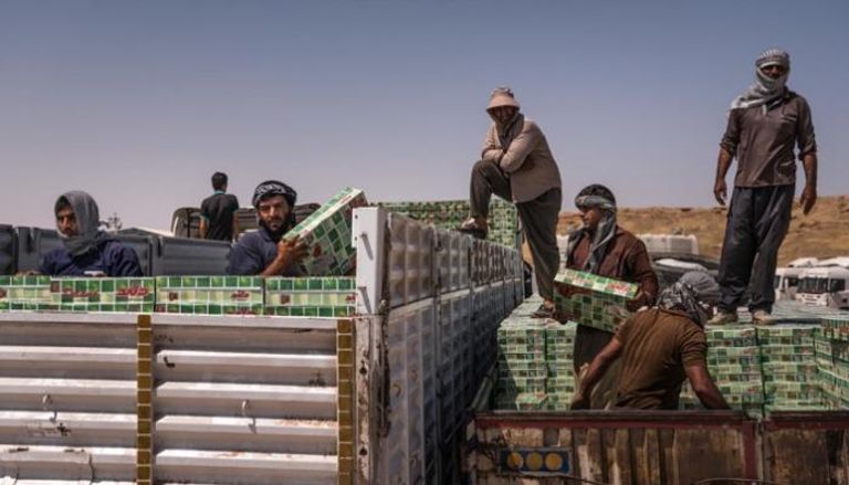 عمال يحملون سلعا إيرانية على معبر حدودي عراقي (نيويورك تايمز)