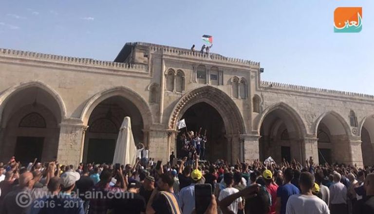 الفلسطينيون يرفعون العلم فوق إحدى بوابات الأقصى