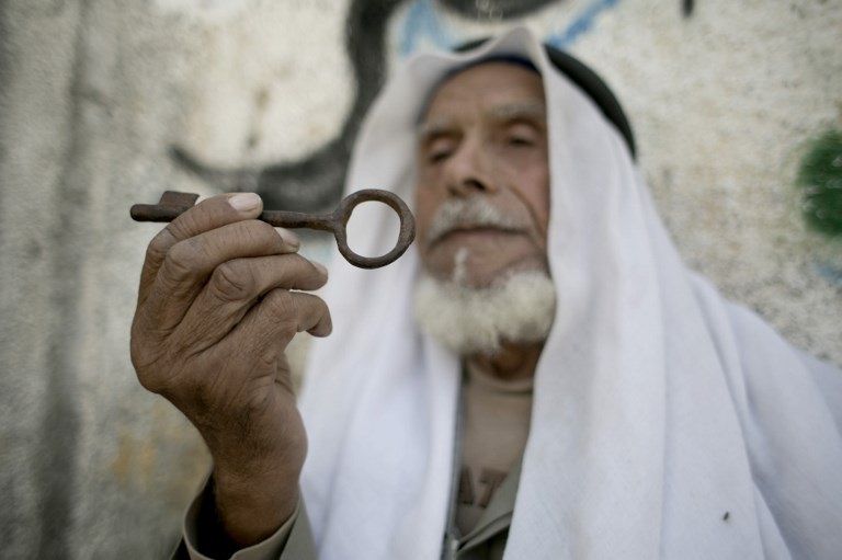 لاجئ فلسطيني ينظر إلى مفتاح منزله الذي غادره على أمل العودة عباس يطالب شعبه بعدم ترك فلسطين للاحتلال (أ.ف.ب)