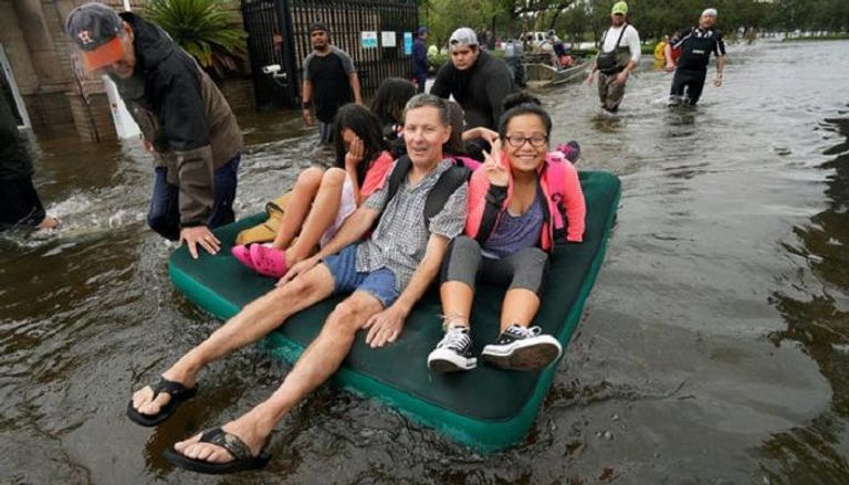 ناجون من الإعصار يبتسمون خلال نقلهم إلى أماكن آمنة (رويترز)