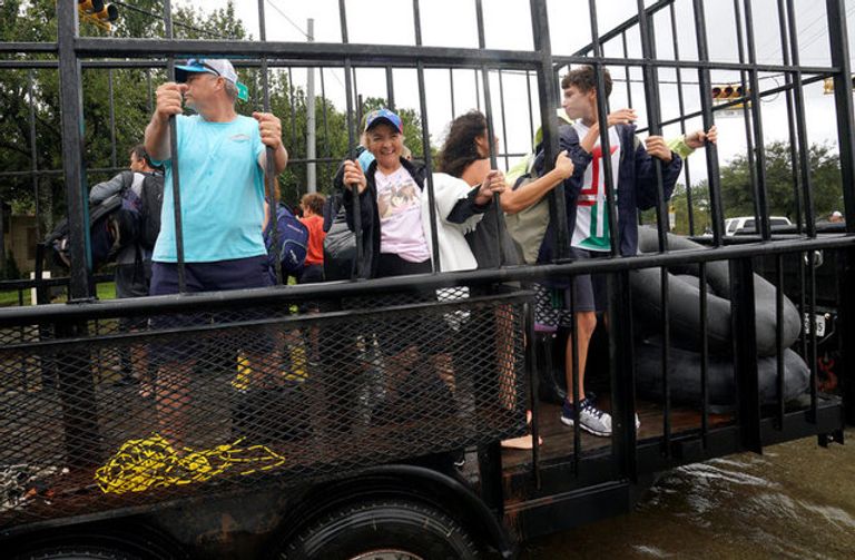 الابتسامة والمرح يهزمان دمار إعصار هارفي ناجون من الإعصار يبتسمون خلال نقلهم إلى أماكن آمنة (رويترز)