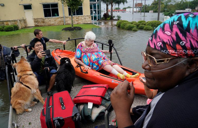 الابتسامة والمرح يهزمان دمار إعصار هارفي ناجون من الإعصار يبتسمون خلال نقلهم إلى أماكن آمنة (رويترز)