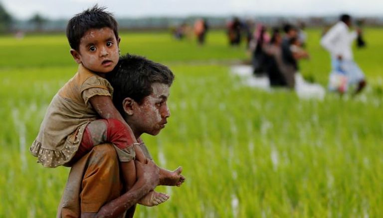 طفل من الروهينغا يحمل آخر بعد عبور حدود بنجلاديش وميانمار