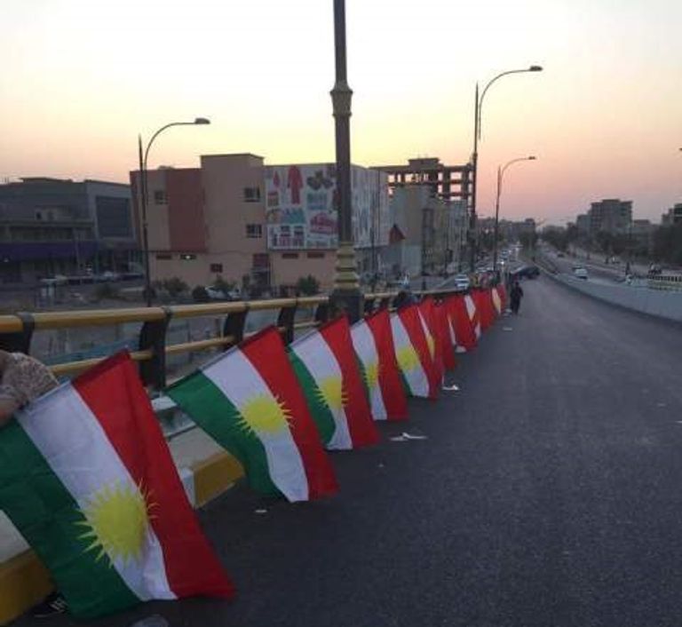 أكراد يرفعون اللافتات التي تدعو للمشاركة في الاستفتاء (رويترز)