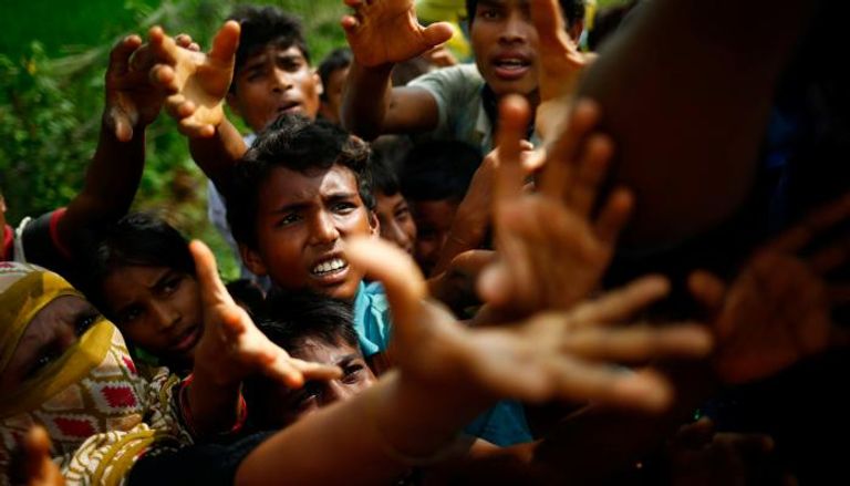 لاجئون من الروهينجا يمدون أيديهم للحصول على طعام في بنجلاديش (رويترز)