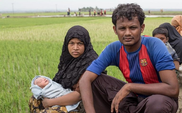 لاجئو الروهينجا يسيرون عبر المياه بعد عبور الحدود إلى بنجلادش