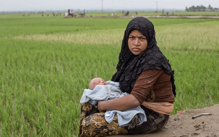 لاجئو الروهينجا يسيرون عبر المياه بعد عبور الحدود إلى بنجلادش