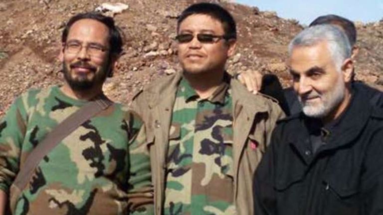 قاسم سليماني قائد فيلق القدس بالحرس الثوري الإيراني مع مقاتلين أجانب أفغان يرفعون صورا لقتلى من