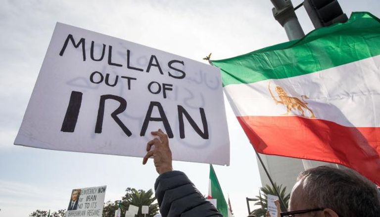 متظاهر يحمل لافتة تطالب بخروج الملالي من إيران- رويترز