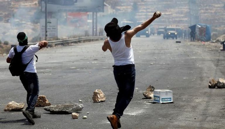شاب فلسطيني يرشق القوات الإسرائيلية بالحجارة