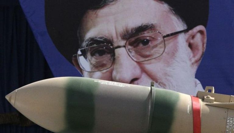 صاروخ إيراني أمام صورة لمرشد إيران خلال استعراض قوة سابق في 2013