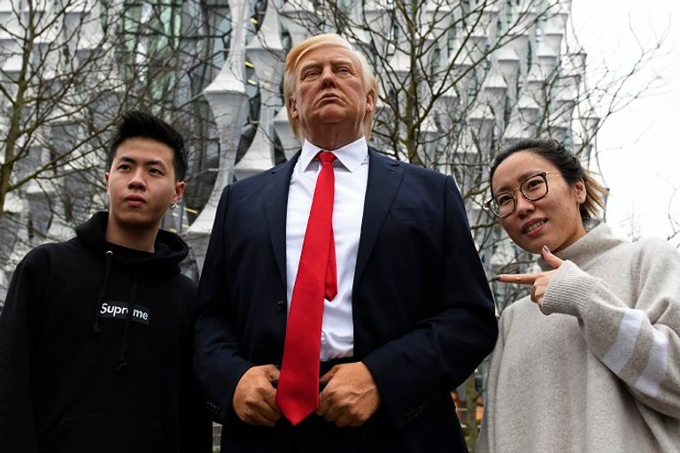 بعض المارة خلال التقاط الصور من تمثال ترامب تمثال الرئيس ترامب أمام مقر السفارة الجديد - أ. ف. ب