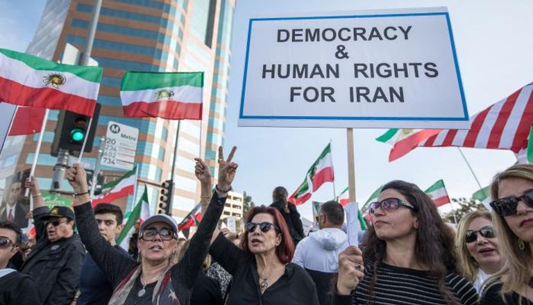 إيرانيات يحملن لافتة كتب عليها الديمقراطية والحرية لإيران - رويترز
